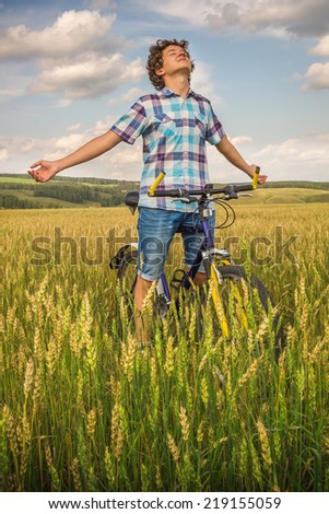 Simple teen boy on a bicycle in a summer field