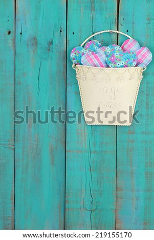 Tin pot of country hearts hanging on antique teal blue rustic wood fence
