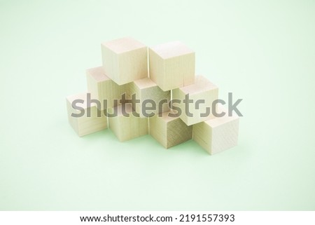 Geometric layout of a pyramid made of wooden cubes on a green background. A symbol of teamwork and growth.