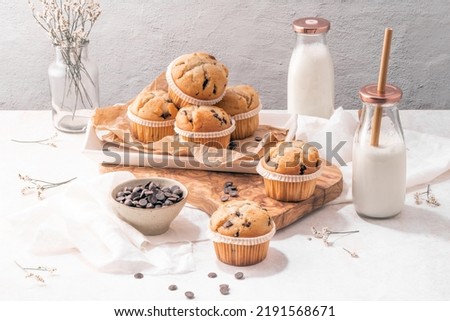 Chocolate chip muffins with milk served on glass bottles on white kitchen countertop. Royalty-Free Stock Photo #2191568671