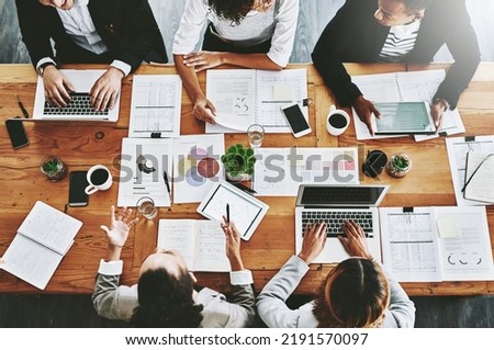 Overhead of colleagues having a marketing meeting in modern office. Above a busy workplace, coworkers brainstorm and develop strategies for a startup business, unity, planning and innovation at work Royalty-Free Stock Photo #2191570097