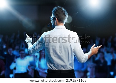 Motivational speaker with headset performing on stage, back view Royalty-Free Stock Photo #2191571105