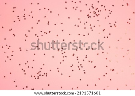 Red star shaped glitter confetti on pink background. Festive flat lay holiday pastel backdrop. Christmas, New Year, party, anniversary, sale, event concept. 