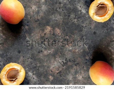 A creative pattern of ripe apricots with a red side and half of apricot with a seed on a black concrete background with copy space. Beautiful fruit background.