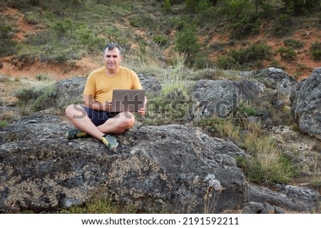 Man working with a laptop sitting on the mountain. Teleworking, freelancing as a lifestyle