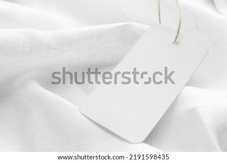 Cardboard tag with space for text on white fabric, closeup