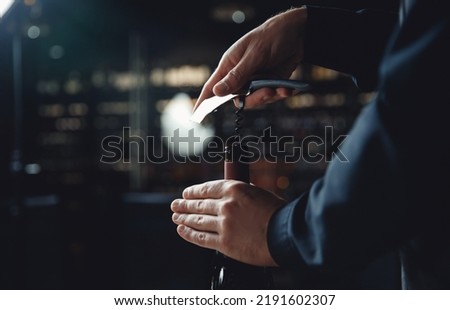 Sommelier opens cork of bottle of red wine with corkscrew. Royalty-Free Stock Photo #2191602307