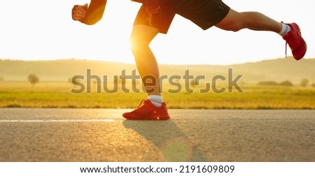 Sprinting man runner sprinter athlete running shoes and legs on track and field lane run race competing fast panoramic banner background.