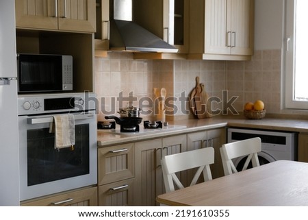 Stylish wooden kitchen with a window, built-in appliances and small beige tile. Close up, copy space, background. Royalty-Free Stock Photo #2191610355