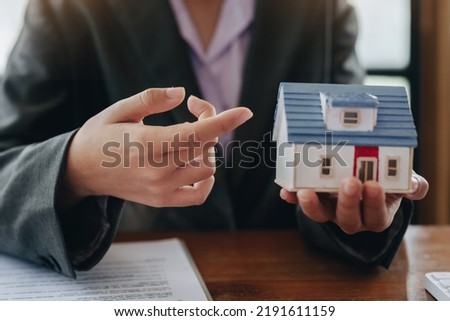 The real estate agent is showing the house model to the customer.