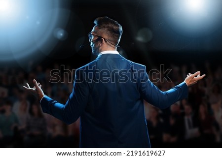 Motivational speaker with headset performing on stage, back view Royalty-Free Stock Photo #2191619627