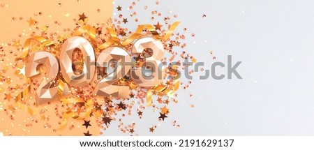 Banner with 2023 golden numbers, ribbons and stars confetti on a blue background. Glittering New Year's concept with place for text.