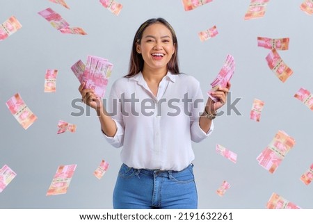 Cheerful young Asian woman holding money banknotes isolated over white background Royalty-Free Stock Photo #2191632261