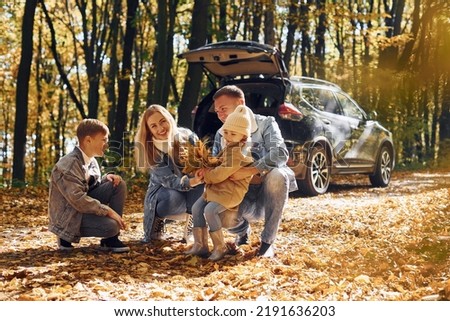 Car is behind. Happy family is in the park at autumn time together. Royalty-Free Stock Photo #2191636203
