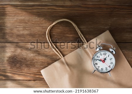 Time to go shopping. Cardboard bag with clock symbolizing the arrival of the sales. Go to the mall and take advantage of seasonal offers