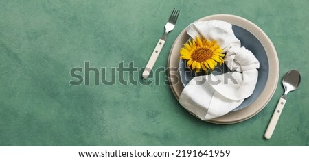 Beautiful table setting with fresh sunflower on green background with space for text, top view