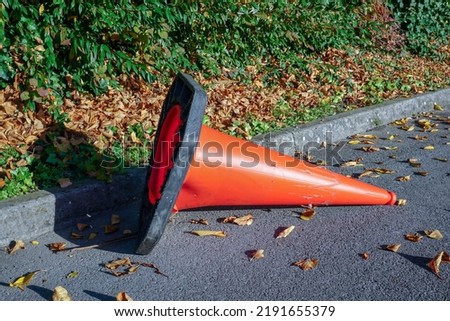 Toppled traffic cone at side of road. Road works safety traffic cone.