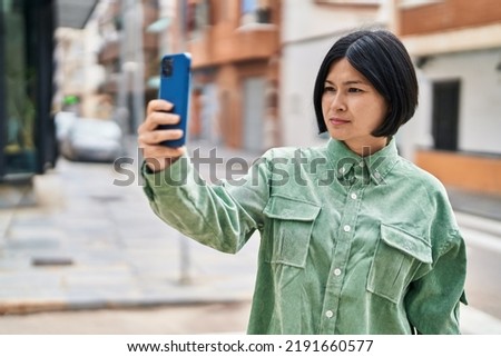Young chinese woman making selfie by the smartphone at street