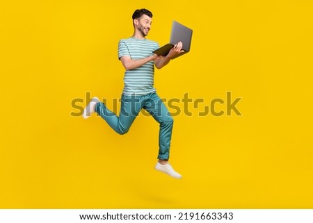 Profile full length photo of impressed guy run with laptop wear t-shirt jeans sneakers isolated on yellow color background