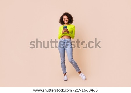 Full size photo of young positive woman hold phone chatting online freelance work isolated on beige color background