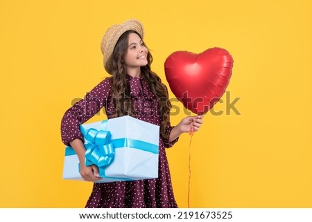 positive teen child with red heart balloon and present box on yellow background