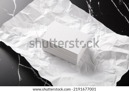 Photo of white business cards on black marble and crumpled paper. Template for branding identity isolated on marble background. 