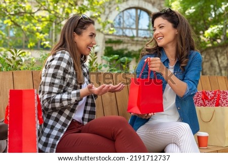 Beautiful women giving gift to her best friend outdoor.