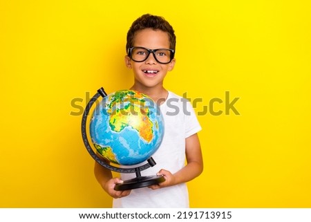 Photo of positive cheerful boy student first lesson hold globe earth isolated on yellow color background