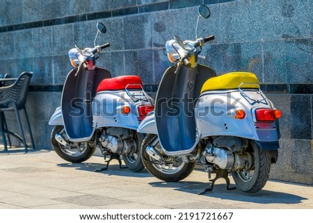 A vintage scooter  - a retro moped is standing in the parking lot. Motor scooter ride. The concept of mobile transport in the city. Royalty-Free Stock Photo #2191721667