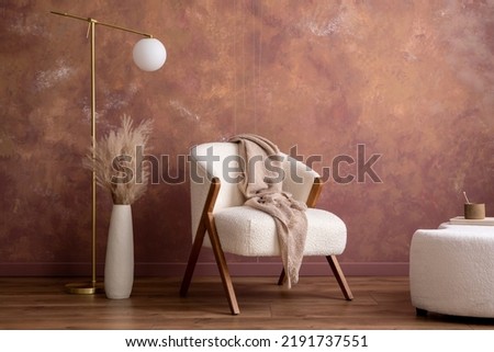 Boho composition a living room interior with white boucle  armchair, design pouf, lamp, vase with dried flowers, gold lamp and personal accessories. Cozy home decor. Template. Copy space. Royalty-Free Stock Photo #2191737551