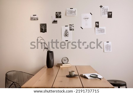 Creative composition of cozy office interior with black chair, wooden table, plants, mock up pictures frames and personal accessories. Home decor. Template.	