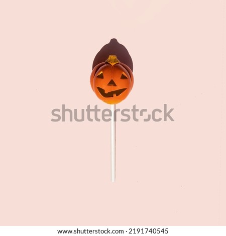 Creative Halloween concept. Scary pumpkin lollipop on pastel bright pink background. Minimalistic holiday composition.