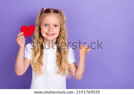 Photo portrait of cute pupil girl tails hold red heart shape point copyspace wear stylish white clothes isolated on violet color background