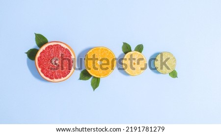 Creative blue background with sliced citrus fruits with green leaves. Flat lay summer tropical concept