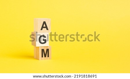 AGM text on wooden block with yellow backgrounds Royalty-Free Stock Photo #2191818691
