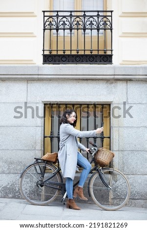 Young Caucasian woman taking a photo with mobile phone next to a classic touring bike. Space for text.
