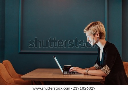 Businesswoman sitting in a cafe while focused on working on a laptop and participating in an online meetings. Selective focus. High quality photo