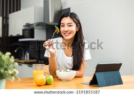 Young female eating organic greens vegetable salad in weight loss diet and wellness on table. Beautiful woman happily eat a healthy salad breakfast in kitchen in the morning. Diet food concept. Royalty-Free Stock Photo #2191855187