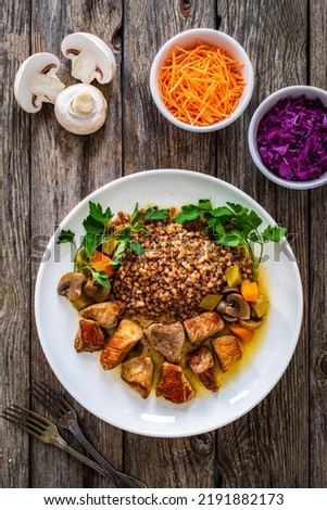 Roast pork with buckwheat groats, mushrooms and carrots served on wooden table  Royalty-Free Stock Photo #2191882173