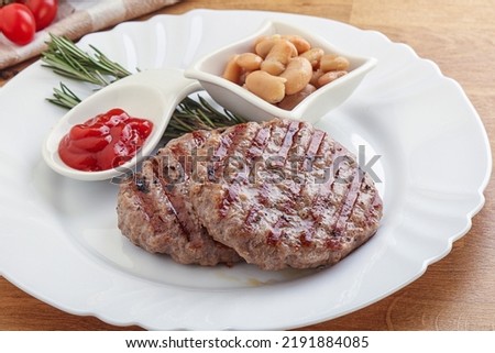 Grilled beef burger cutlet with sauce and beans