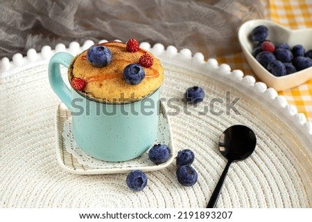 Delicious homemade blueberry muffin mug cake with fresh berries . Cooked in a cup in the microwave. cupcake in a blue mug decorated with blueberries. vanilla mugcake dessert. Easy to cook concept Royalty-Free Stock Photo #2191893207