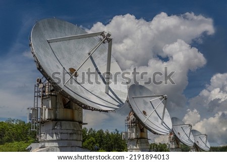 Group of millimeter wave interferometer antennas lined up against backdrop of cloudy blue sky. Images of Universe, Observations, Unknowns, Future, and Hope Royalty-Free Stock Photo #2191894013