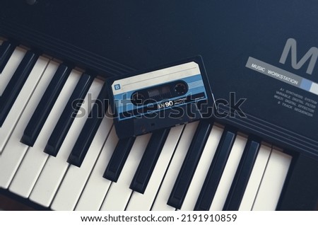Vintage audio tape cassette on a synthesizer keys from above,Retro cassette.Audio equipment for analog music records. Black stereo tape. Isolated plastic musical device. Old-fashioned mixtape of tunes