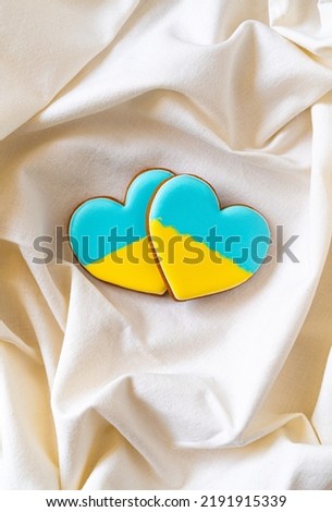 Two Heart shape ukrainian colours blue and yellow national flag gingerbread cookies on textile bakground. Flat lay, copy space
