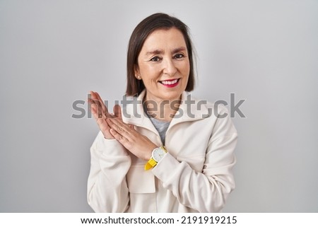 Middle age hispanic woman standing over isolated background clapping and applauding happy and joyful, smiling proud hands together 