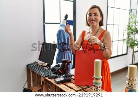 Middle age hispanic woman paying with credit card at retail shop
