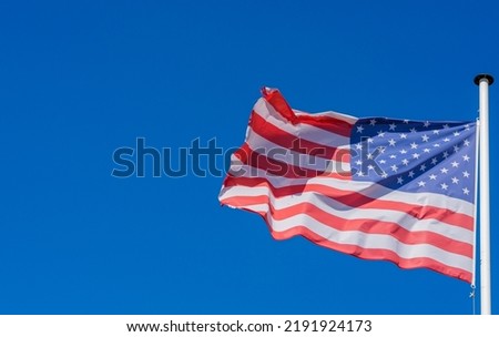 American flag raised against clear blue skies.
