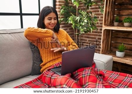 Young latin woman having video call using deaf sign language at home