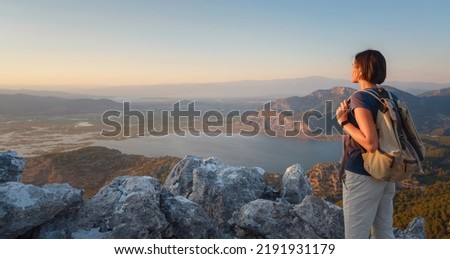 Travel to Turkey, viewpoint over Dalyan Iztuzu Beach. . Smiling woman taking break on hiking trip looking at view at sunset. Explore natural wonders of Turkey