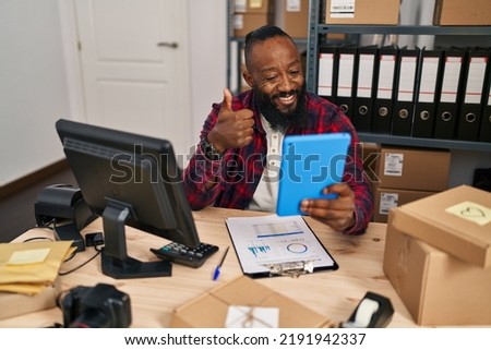 African american man working at small business ecommerce doing video call smiling happy and positive, thumb up doing excellent and approval sign 